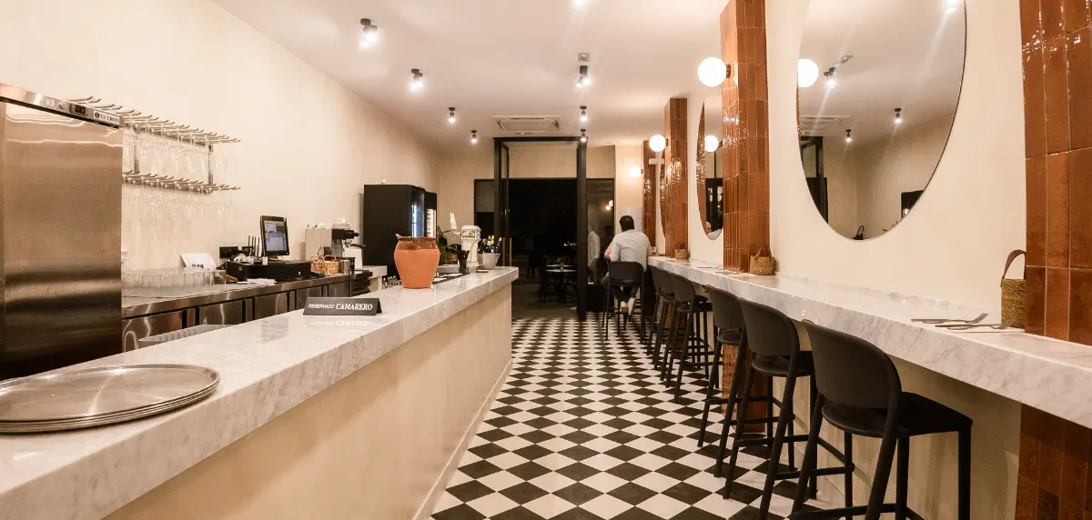 Interior de La Barra de Consuelo, bar de tapas en Utrera, con barra de mármol y suelo de damero